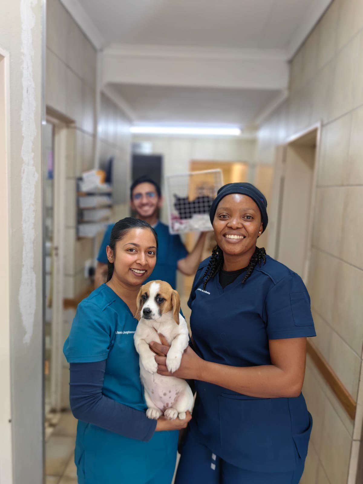 Two of the team with a puppy in the hospital passage