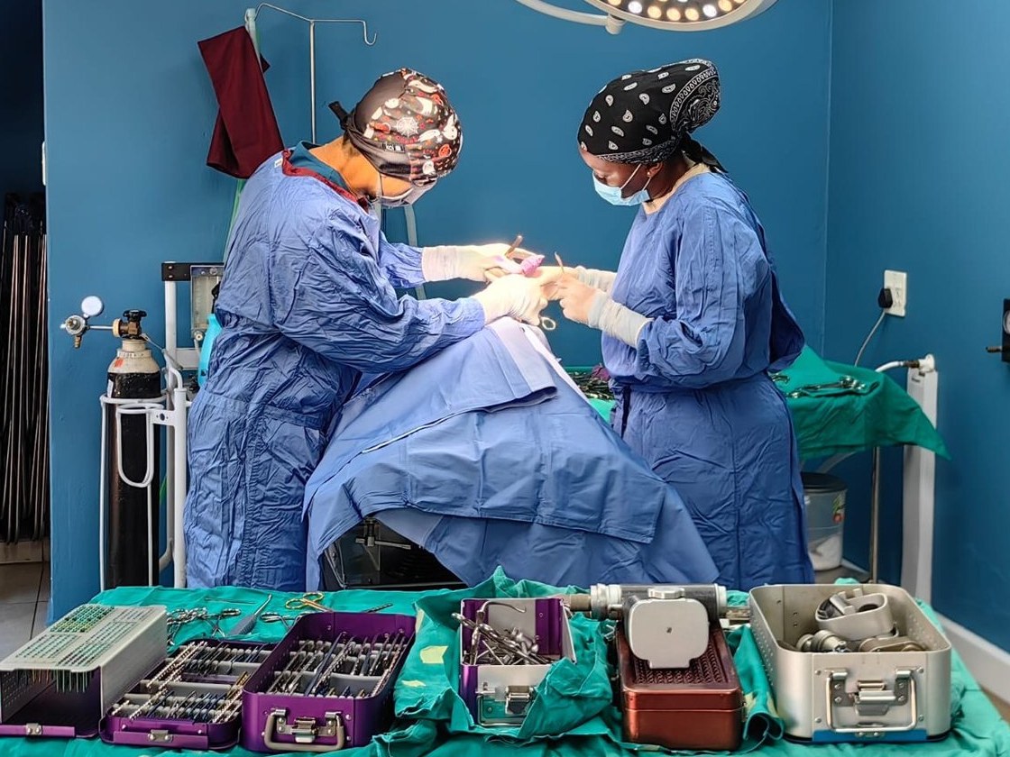 Two of the team operating in theatre, with orthopaedic instrument sets laid out